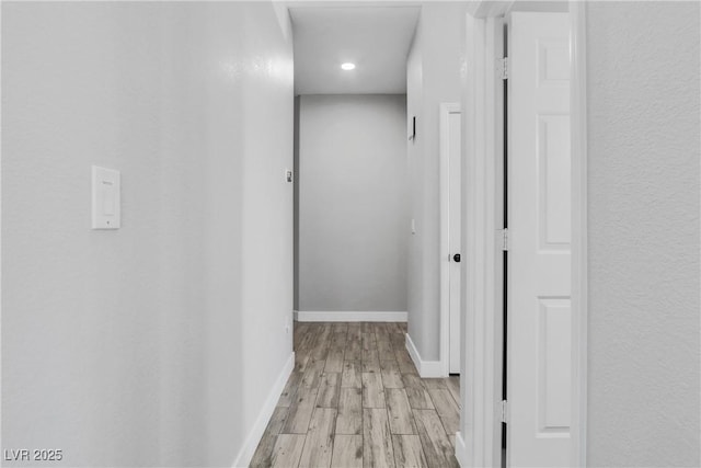 hallway featuring light wood-type flooring and baseboards