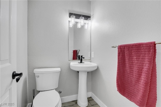 bathroom with toilet, baseboards, and a sink