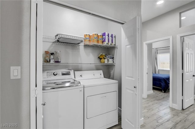 washroom featuring laundry area, washing machine and dryer, light wood-style floors, and baseboards