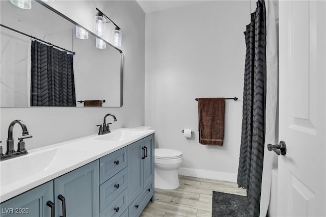 full bath with double vanity, toilet, wood finished floors, and a sink