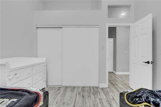 bedroom with light wood finished floors, baseboards, and a closet