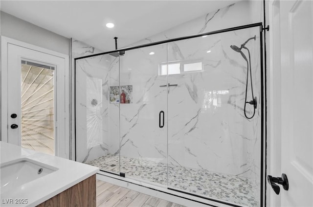 bathroom featuring a marble finish shower, recessed lighting, vanity, and wood finished floors