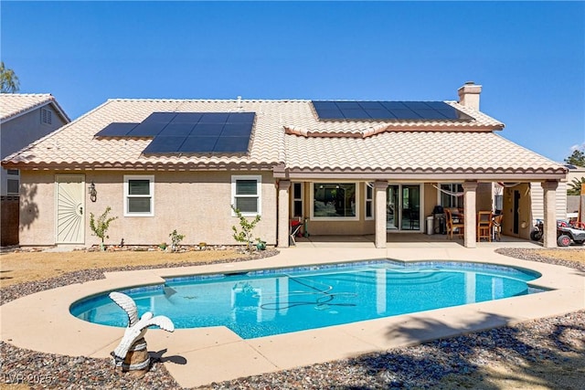 rear view of house featuring a tiled roof, a patio area, an outdoor pool, and a chimney