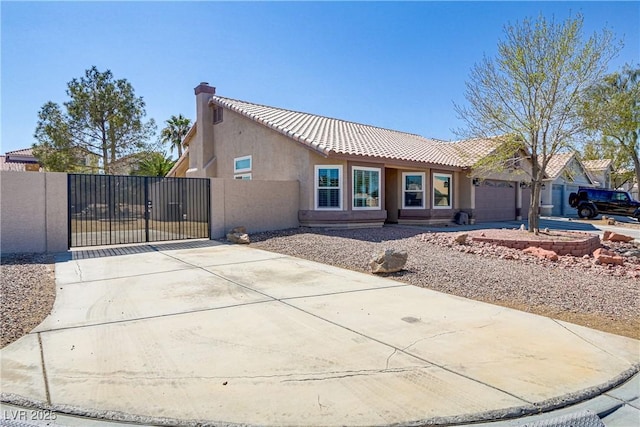 view of front of house with a gate, driveway, stucco siding, a chimney, and a tile roof