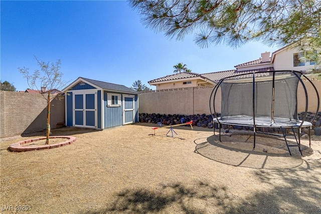 view of yard with a fenced backyard, a trampoline, an outdoor structure, and a shed