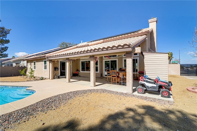 back of house featuring a tiled roof, stucco siding, a chimney, a fenced backyard, and a patio