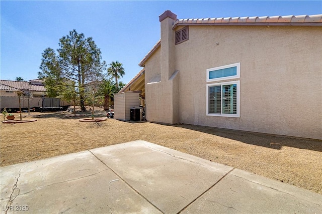 rear view of house featuring fence, a tile roof, central AC, stucco siding, and a patio area