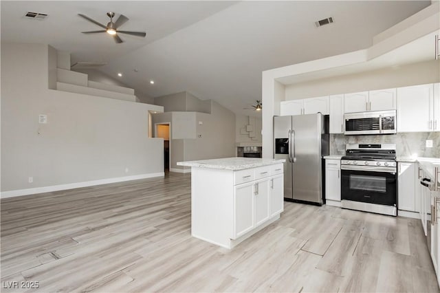 kitchen with open floor plan, appliances with stainless steel finishes, decorative backsplash, ceiling fan, and vaulted ceiling