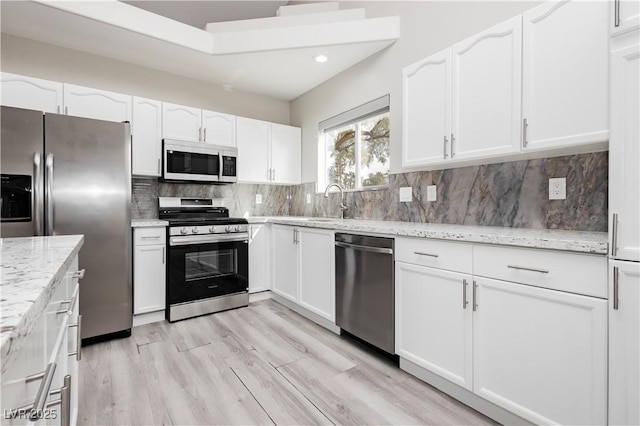 kitchen featuring light stone counters, decorative backsplash, appliances with stainless steel finishes, and white cabinetry