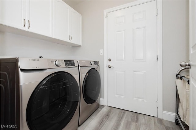 laundry room with light wood-type flooring, cabinet space, baseboards, and washing machine and dryer