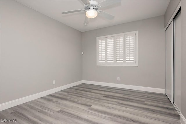 unfurnished bedroom with a ceiling fan, wood finished floors, baseboards, and a closet