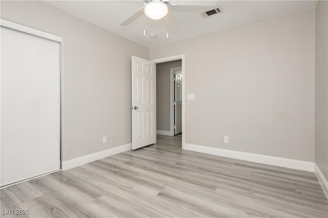 unfurnished bedroom with baseboards, visible vents, light wood-style flooring, ceiling fan, and a closet