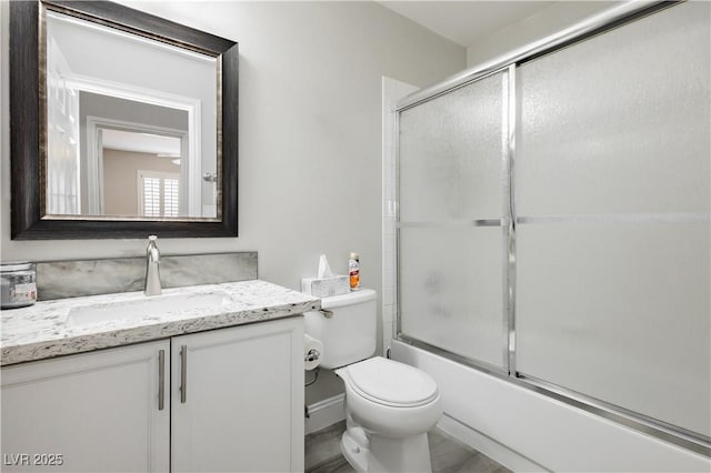 bathroom with vanity, toilet, and combined bath / shower with glass door