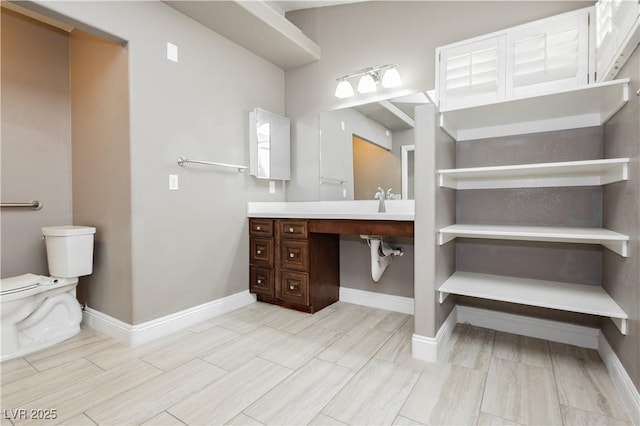 bathroom featuring vanity, toilet, and baseboards