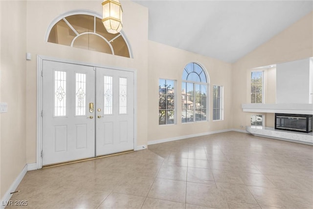 foyer with baseboards, high vaulted ceiling, a fireplace, and tile patterned flooring