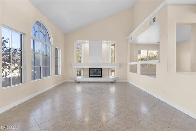 unfurnished living room with visible vents, baseboards, high vaulted ceiling, and a glass covered fireplace