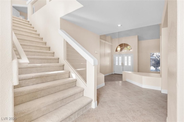 entrance foyer featuring stairs, french doors, baseboards, and tile patterned flooring