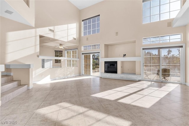 unfurnished living room with a glass covered fireplace, tile patterned floors, a ceiling fan, and visible vents