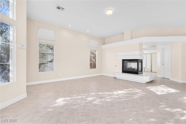 unfurnished living room featuring recessed lighting, visible vents, baseboards, and a multi sided fireplace