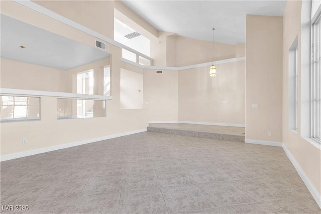 spare room featuring visible vents, baseboards, and high vaulted ceiling