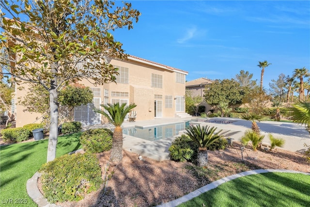 exterior space featuring stucco siding, an outdoor pool, and a lawn