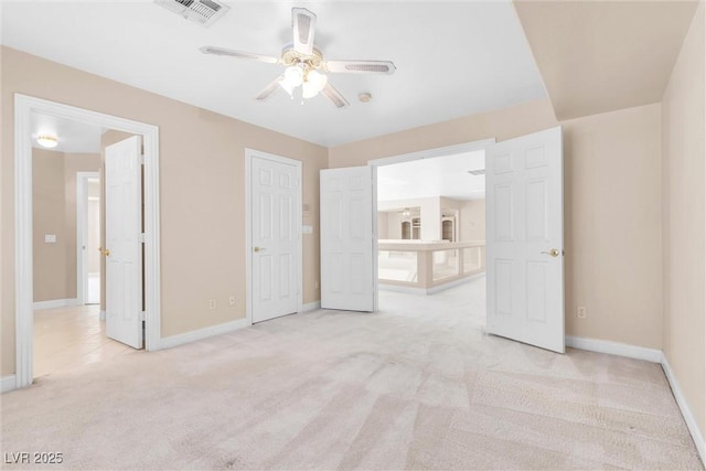 unfurnished bedroom featuring visible vents, light carpet, baseboards, and a ceiling fan