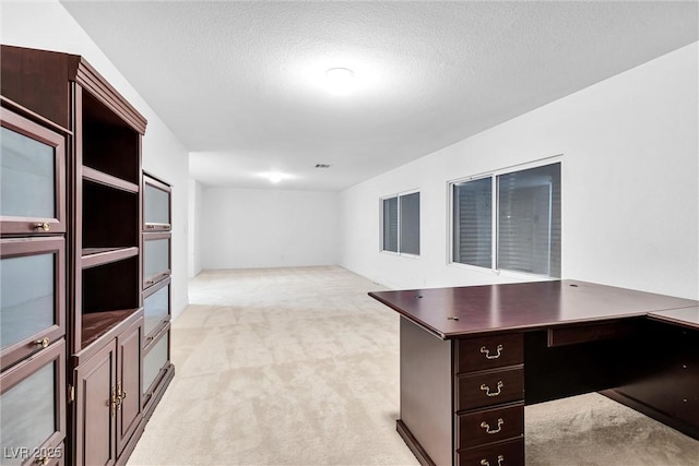 unfurnished office featuring visible vents, light carpet, and a textured ceiling