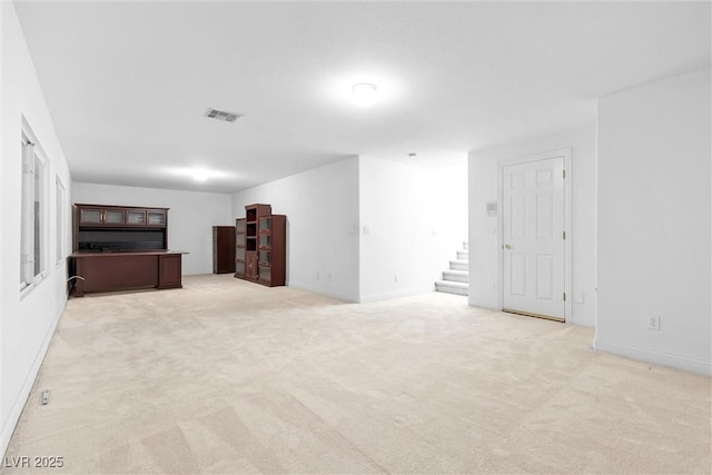 unfurnished living room with visible vents, light carpet, baseboards, and stairway