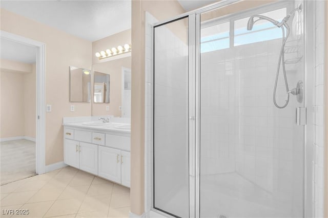 bathroom featuring vanity, tile patterned floors, baseboards, and a stall shower