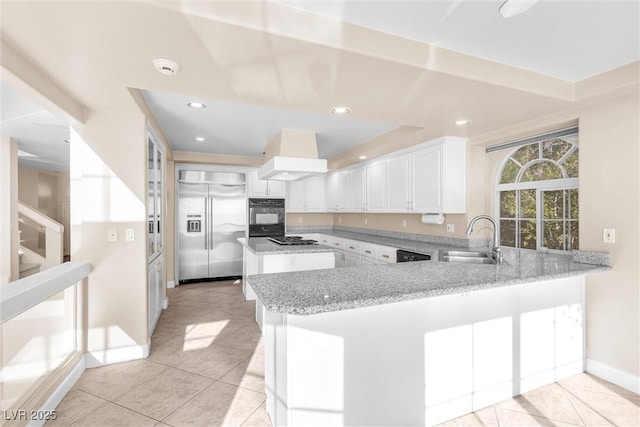 kitchen featuring gas cooktop, light stone countertops, a sink, built in fridge, and white cabinetry