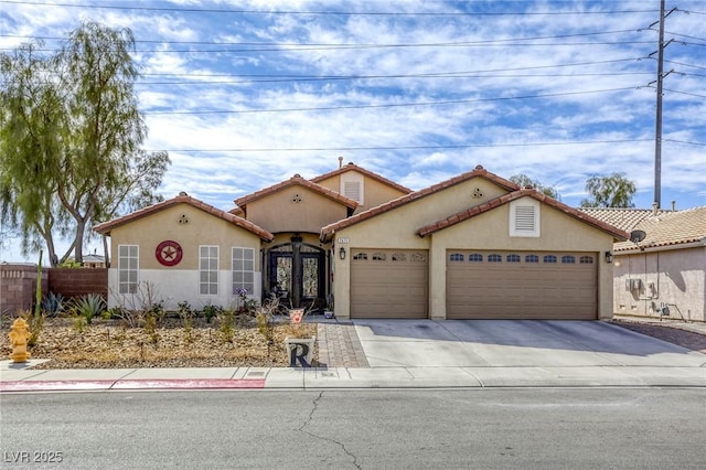 mediterranean / spanish-style home with fence, a garage, driveway, and stucco siding