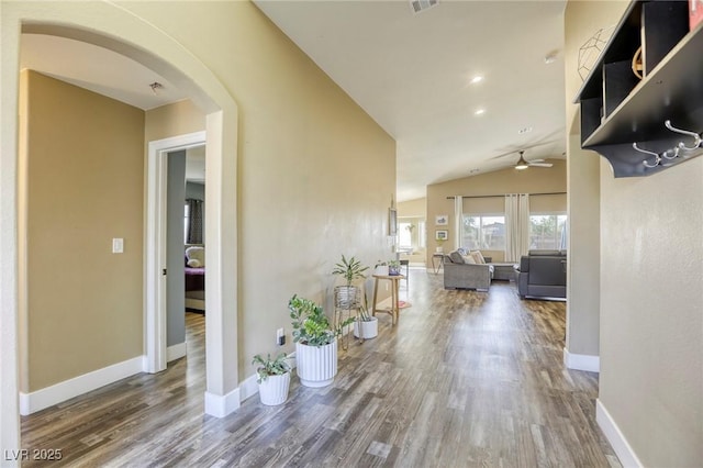 hall with arched walkways, vaulted ceiling, baseboards, and wood finished floors