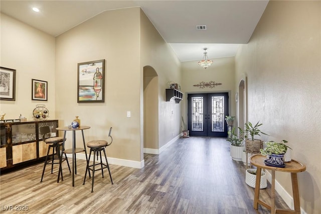 foyer entrance featuring wood finished floors, visible vents, arched walkways, and french doors