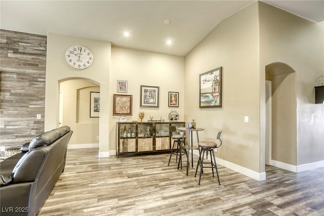 interior space featuring recessed lighting, baseboards, arched walkways, and wood finished floors