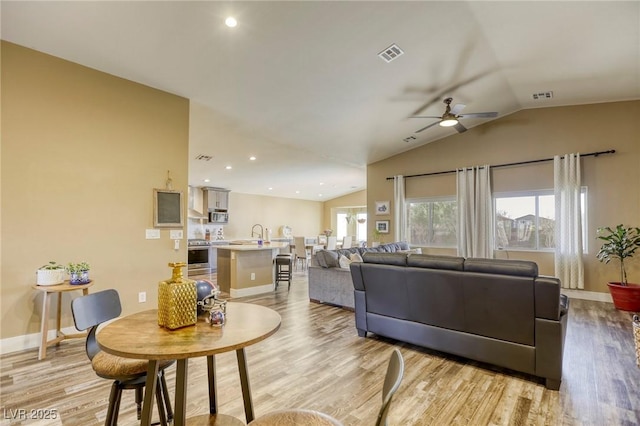 living room with visible vents, lofted ceiling, a ceiling fan, and light wood finished floors