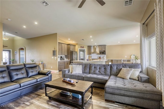 living area with lofted ceiling, a ceiling fan, visible vents, and light wood-type flooring