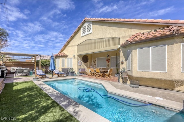 rear view of house featuring stucco siding, a patio, a fenced in pool, and a tiled roof