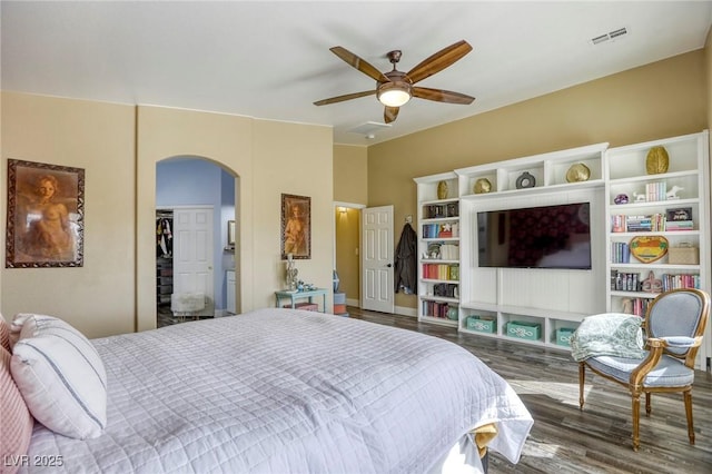 bedroom featuring wood finished floors, visible vents, arched walkways, and ceiling fan