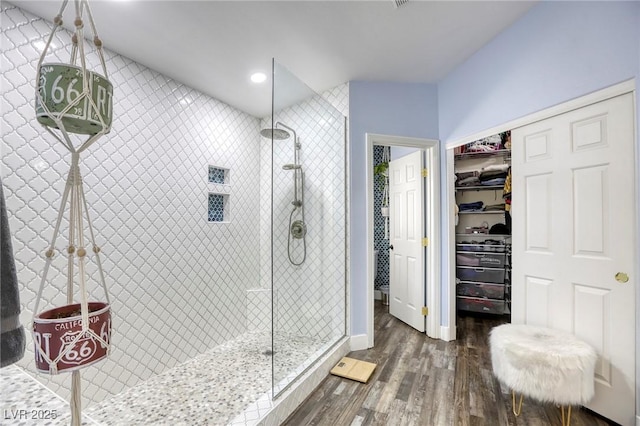 full bath with a spacious closet, recessed lighting, walk in shower, and wood finished floors