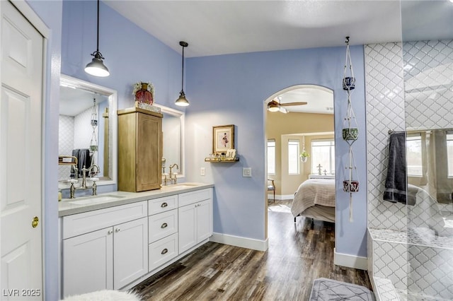 ensuite bathroom featuring wood finished floors, a tile shower, ensuite bathroom, and a sink