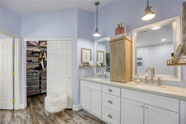 bathroom featuring double vanity, wood finished floors, tasteful backsplash, and a sink