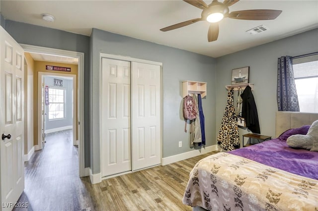 bedroom featuring visible vents, baseboards, ceiling fan, light wood-style floors, and a closet