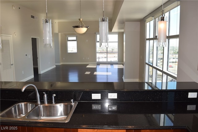 kitchen featuring visible vents, a sink, wood finished floors, open floor plan, and baseboards