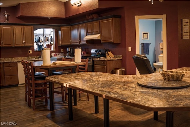 kitchen featuring dark wood-type flooring, white dishwasher, under cabinet range hood, and stainless steel gas range oven