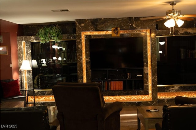 living room featuring wood finished floors, visible vents, and ceiling fan