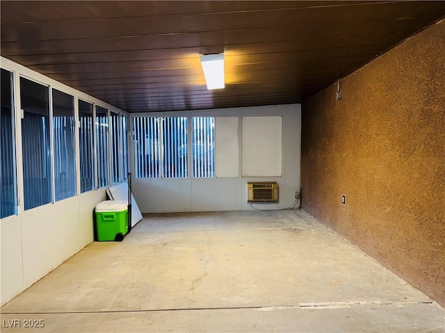 interior space with unfinished concrete flooring, a textured wall, and a wall mounted air conditioner