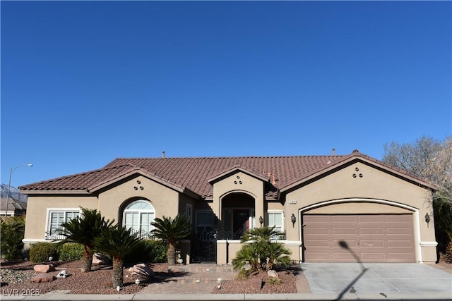 mediterranean / spanish-style home featuring stucco siding, a garage, driveway, and a tile roof