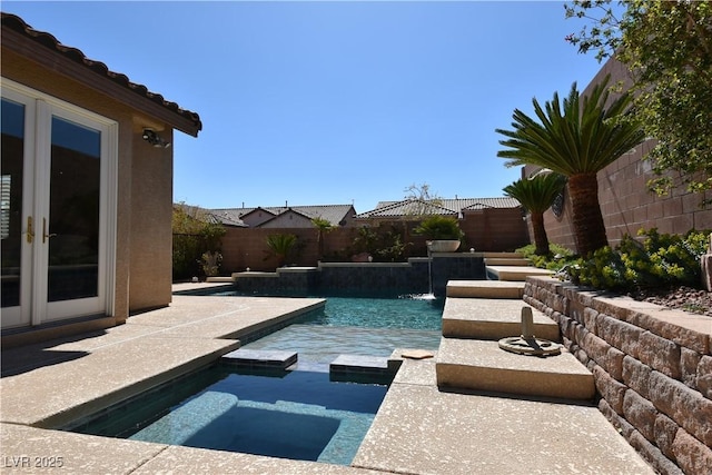 view of pool featuring a patio area, a pool with connected hot tub, french doors, and a fenced backyard