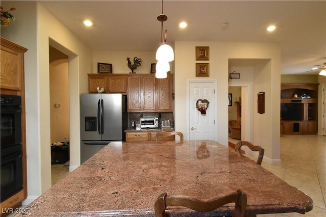 kitchen with recessed lighting, a large island, dobule oven black, decorative light fixtures, and stainless steel fridge