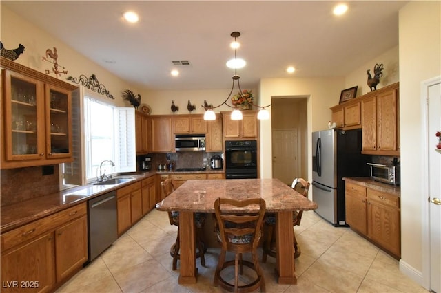 kitchen with brown cabinetry, black appliances, tasteful backsplash, and a sink